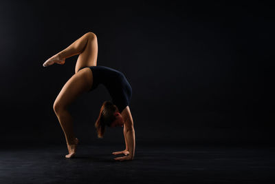 Full length of woman jumping against black background