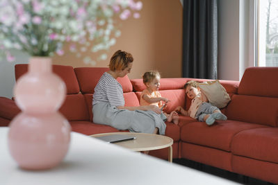 Mother reading book with two kids on sofa. happy family moments at home. spending time and educating