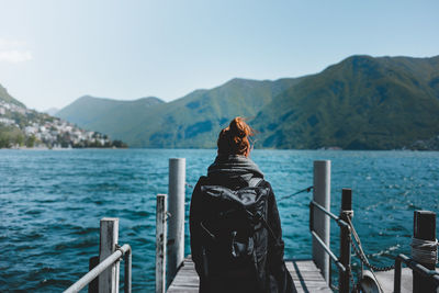 Rear view of woman standing on pier against sea