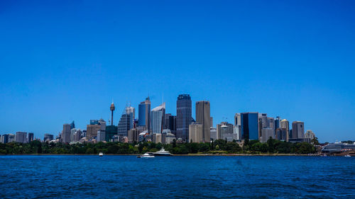 City at waterfront against blue sky