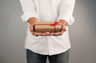 Midsection of man holding paper while standing against white background