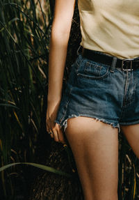 Midsection of woman standing against plants