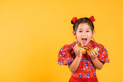 Portrait of cute girl standing against yellow background