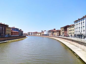 Canal amidst buildings against clear blue sky