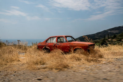 Red car on land against sky