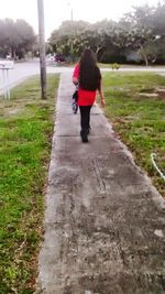 Rear view of woman walking on footpath