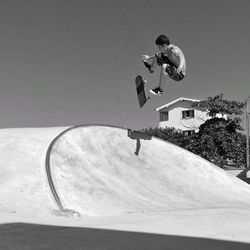 Man skateboarding on skateboard against clear sky