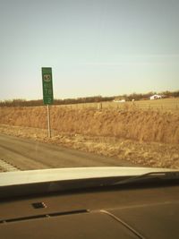 Road by field against clear sky