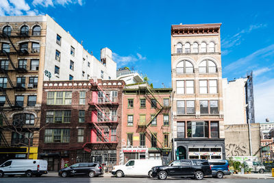 Cars on road by buildings against blue sky