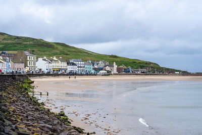 Scenic view of beach by buildings against sky