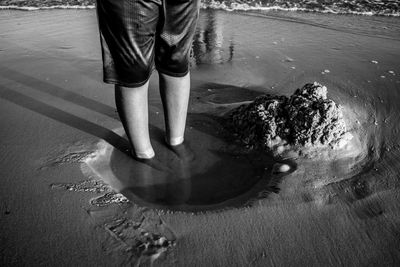 Low section of person standing in water at beach