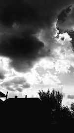 Low angle view of silhouette trees against cloudy sky