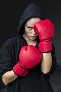 Determined young female athlete in red boxing gloves