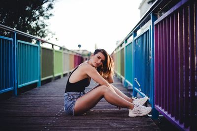 Portrait of woman sitting on railing