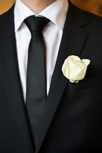 Midsection of bridegroom with rose 