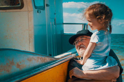 Grandfather and granddaughter by boat at beach