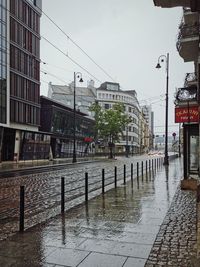 Street by buildings against sky during rainy season