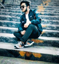 Full length of young man sitting on wall