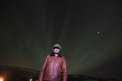 Portrait of man sitting against sky at night