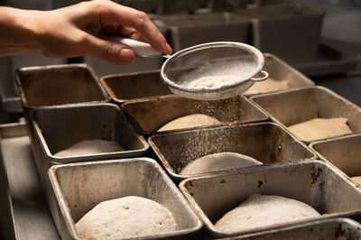 Close-up of female hands sprinkling a piece of raw dough in a baking form with flour. prepare the