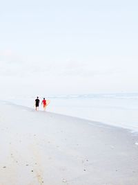 Rear view of people walking with surfboard at beach