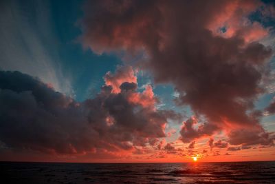 Scenic view of sea against dramatic sky during sunset