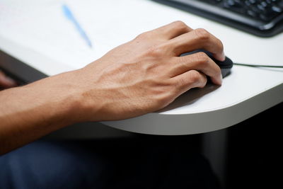 Close-up of man holding computer mouse on table