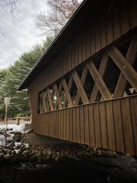 Built structure by trees against sky during winter