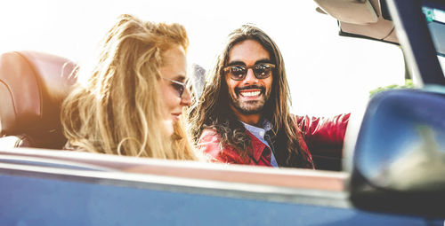 Couple wearing sunglasses sitting in convertible