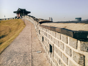 Footpath by building against clear sky