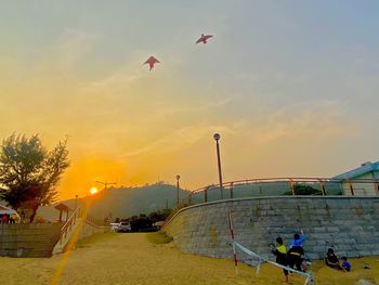 People at commercial dock against sky during sunset