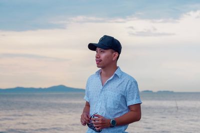 Man looking away while standing against sea