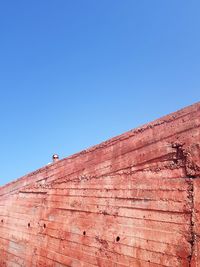 Low angle view of brick wall against blue sky