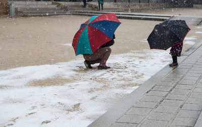 Rear view of people walking on wet road during winter