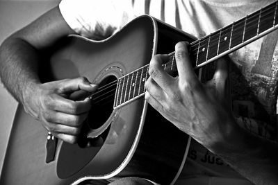 Midsection of man playing guitar