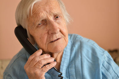 Close-up of a 90-year-old elderly retired woman who is talking smiling on the phone. selective focus