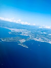 Aerial view of city by sea against blue sky
