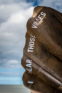 Close-up of information sign against sky