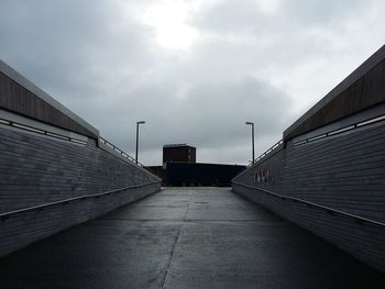 Walkway by water against sky