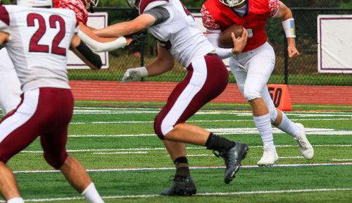 Lineman blocking for the running back during a high school football game.