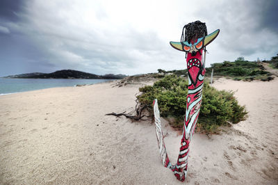 Scenic view of painted wooden post on beach against sky