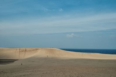 Sand dunes at beach against sky