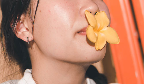 Close-up of young woman holding flower in mouth outdoors