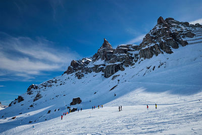 Group of people on snowcapped mountain against sky