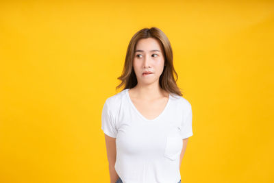 Portrait of beautiful young woman against yellow background