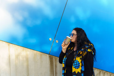 Low angle view of young woman standing against sky