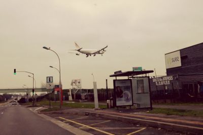 Birds flying over road against sky