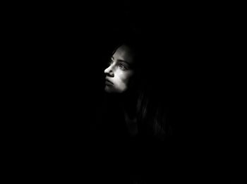 Young woman looking away against black background