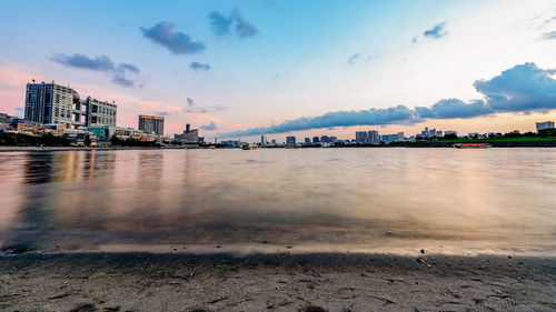 Scenic view of river by buildings against sky