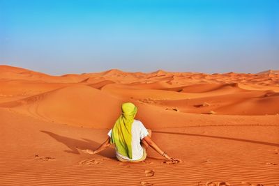 Rear vie of woman sitting at desert